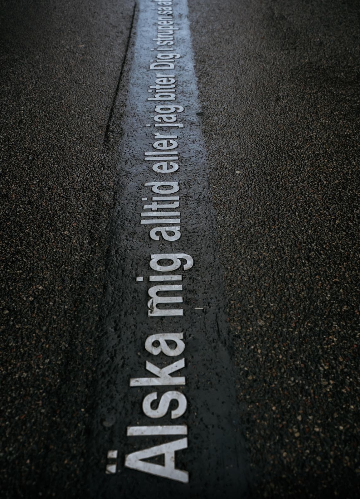 Inscription « Älska mig alltid » sur le bitume